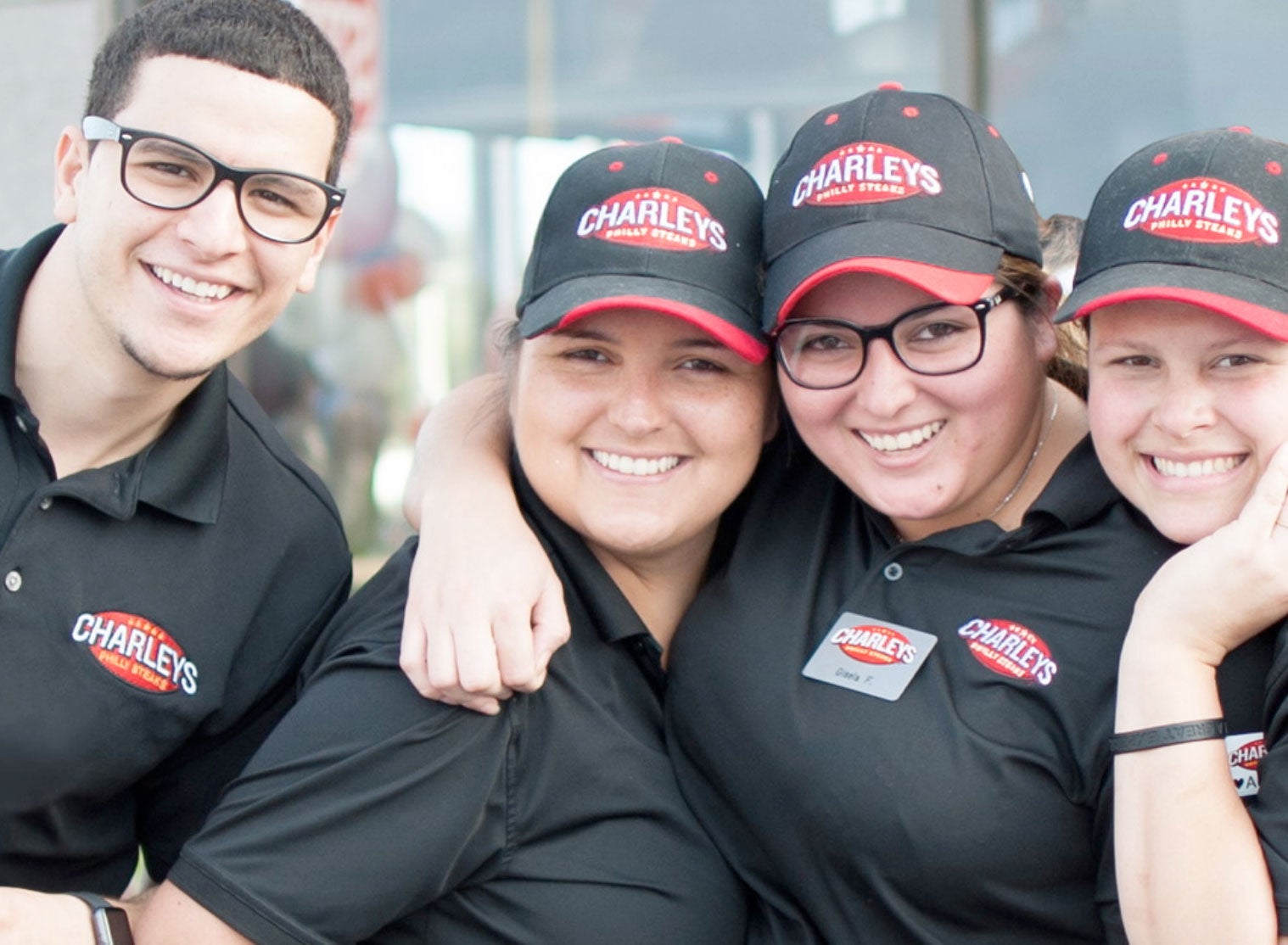 Four Charleys team members smiling and laughing while wearing uniforms. 